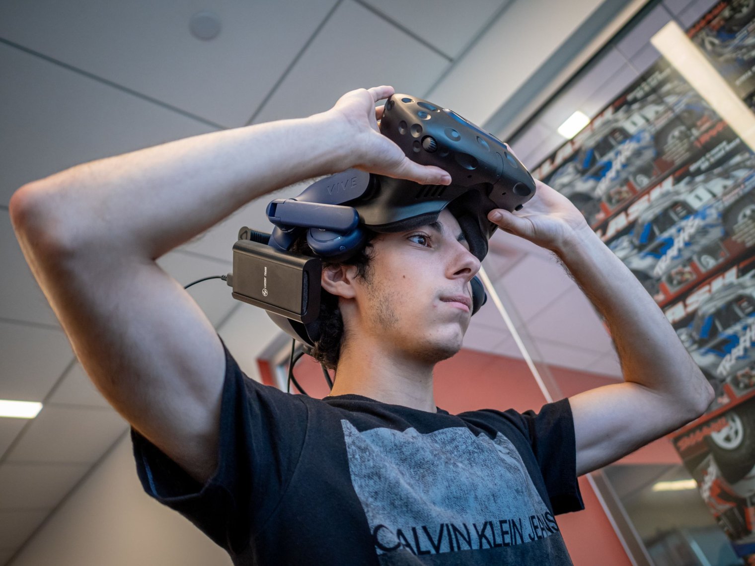 Student lifts a virtual reality headset to show his face.