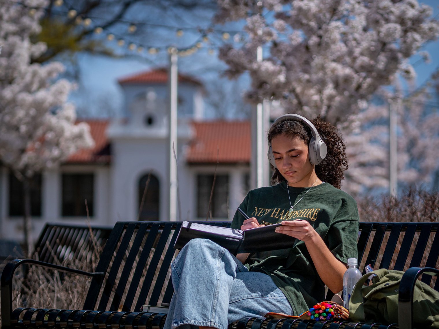 Student working on their notbook while sitting outside on a bench.