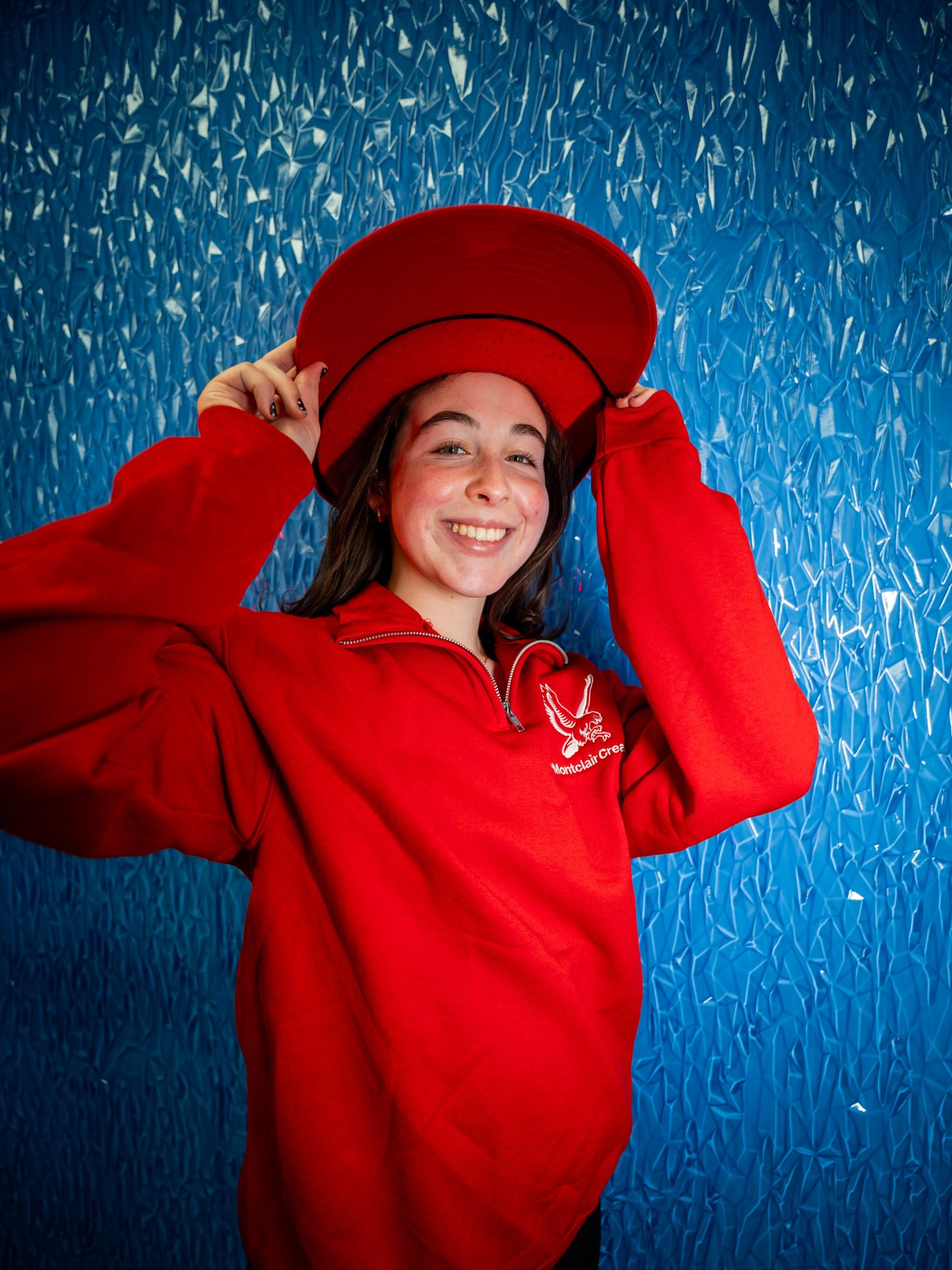 Photo of a young woman in a red Montclair sweatshirt and a unreasonably large baseball cap