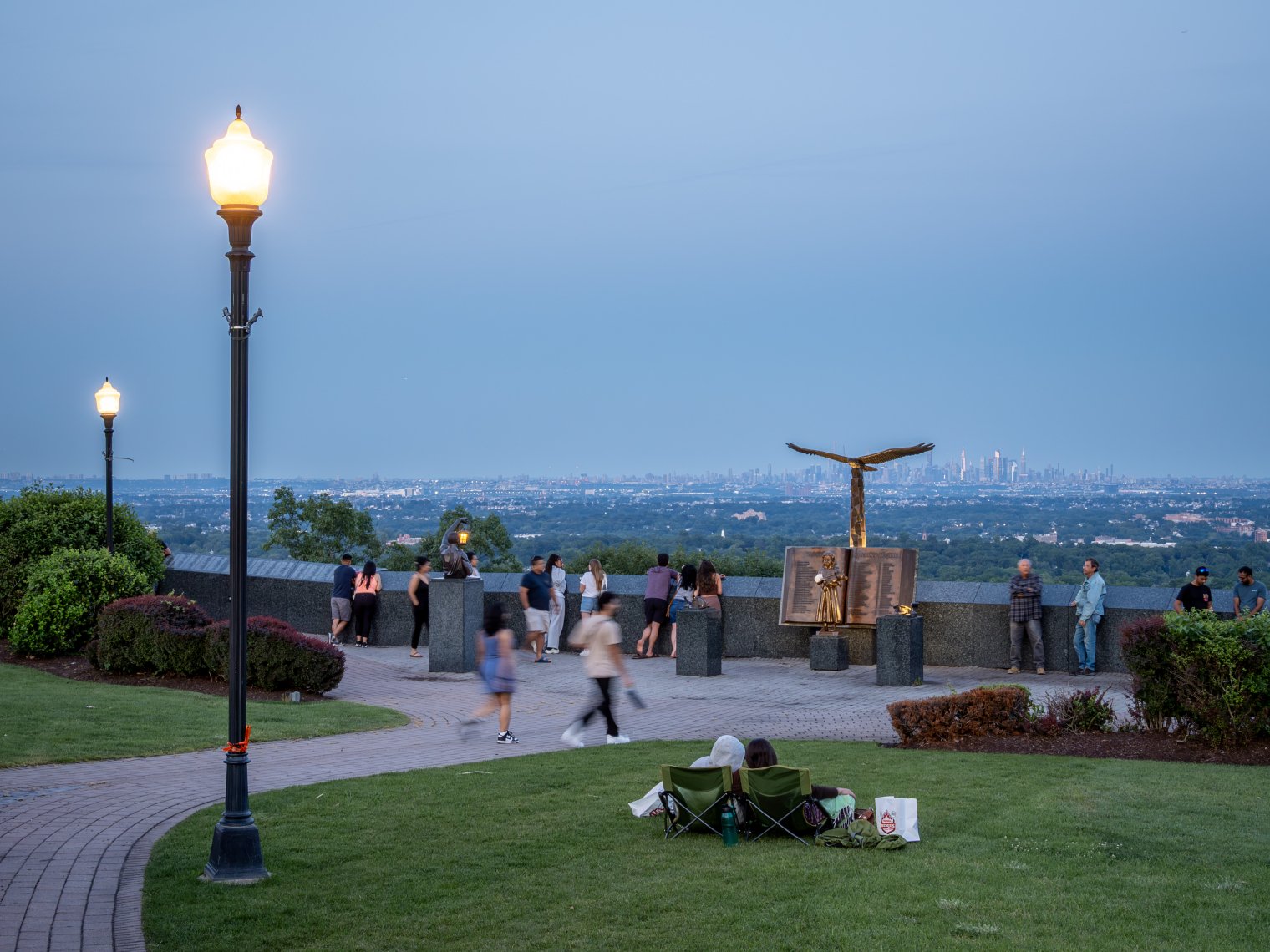 Visitors enjoy outdoor activities at the Eagle Rock Observation Deck against the backdrop of the Manhattan skyline.