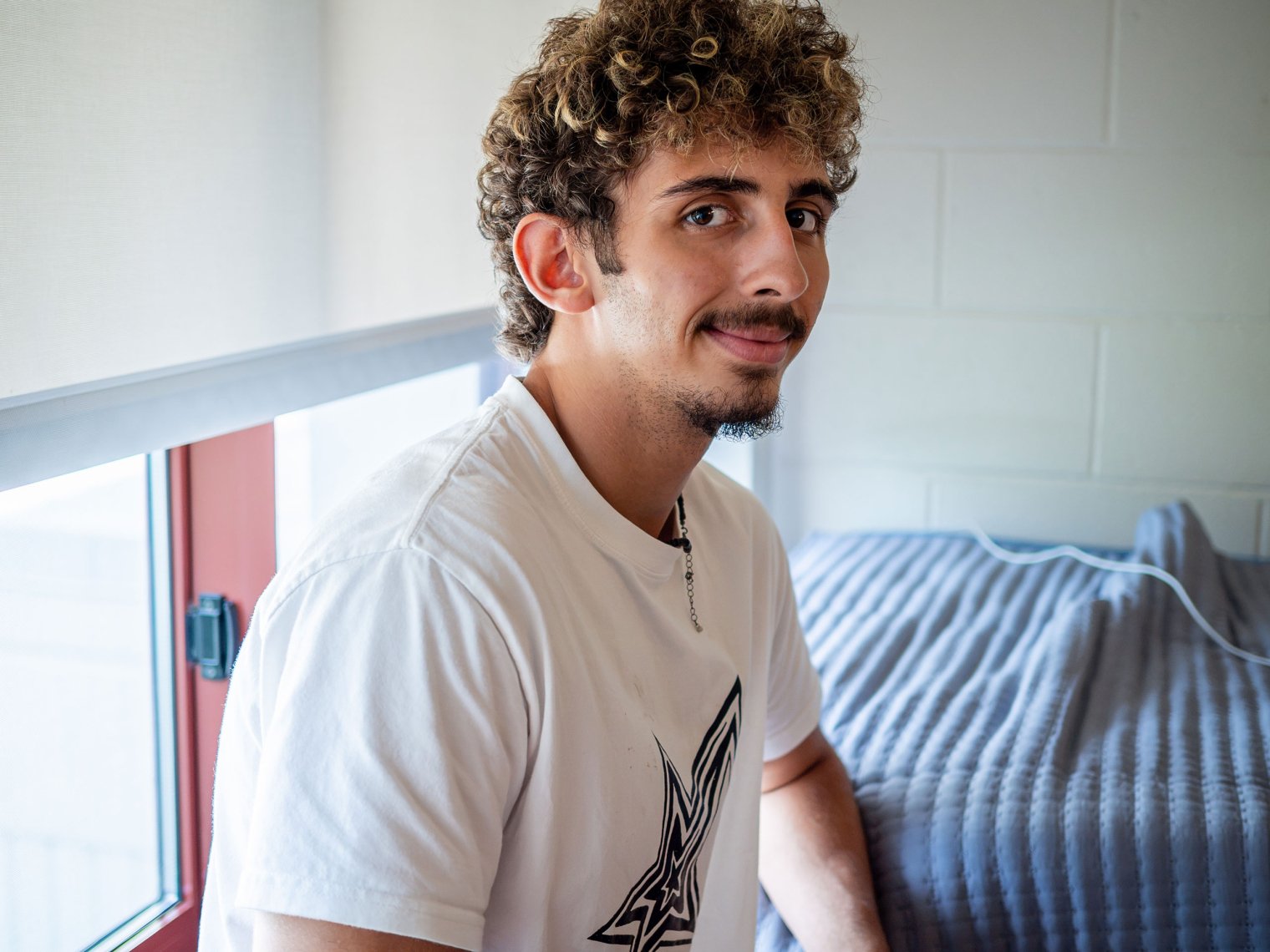  Adam Abdelwahed looks at the camera while sitting on a ledge in his dorm room.