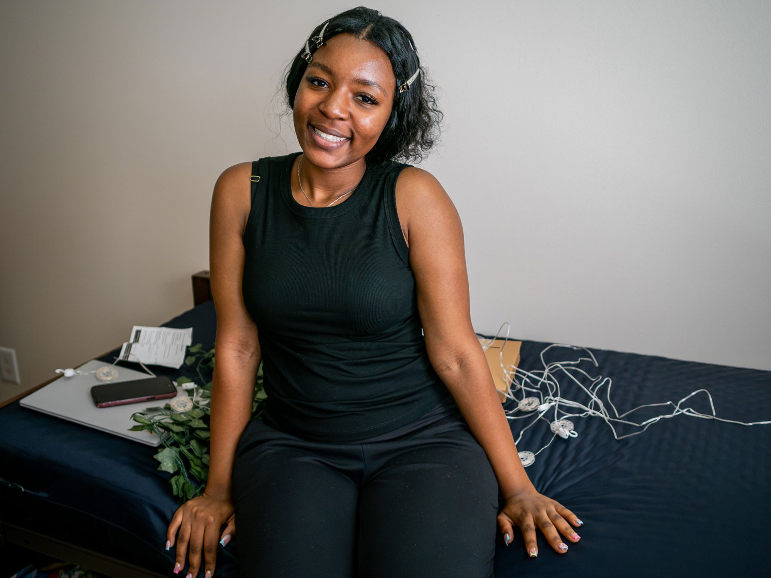 Michaella Mbaye sits on her bed in her dorm room.
