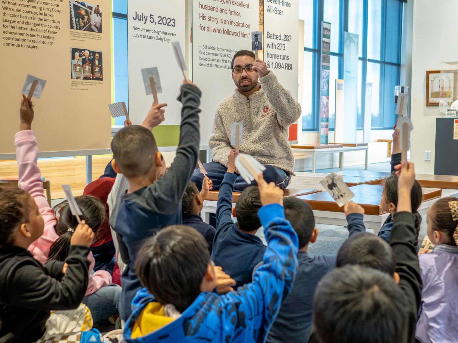 Children sitting in front of instructor, all raising hands
