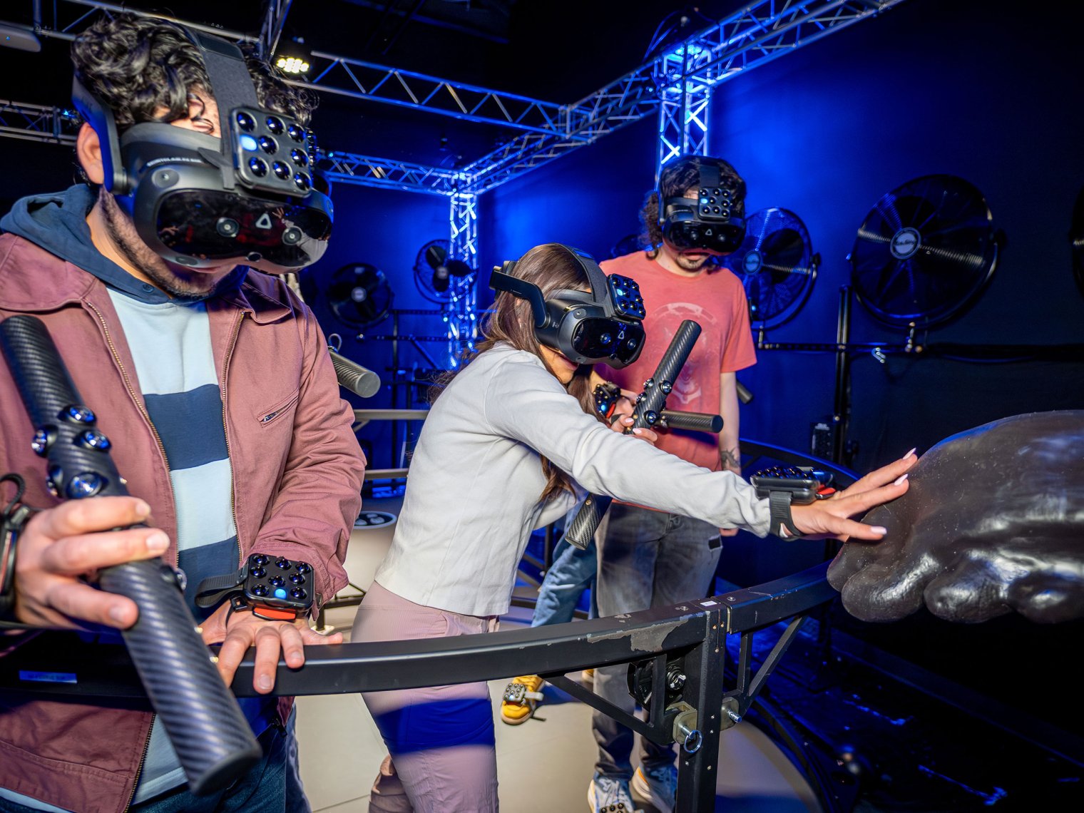 Three students wearing VR headsets interacting with physical accessories in the Dreamscape environment
