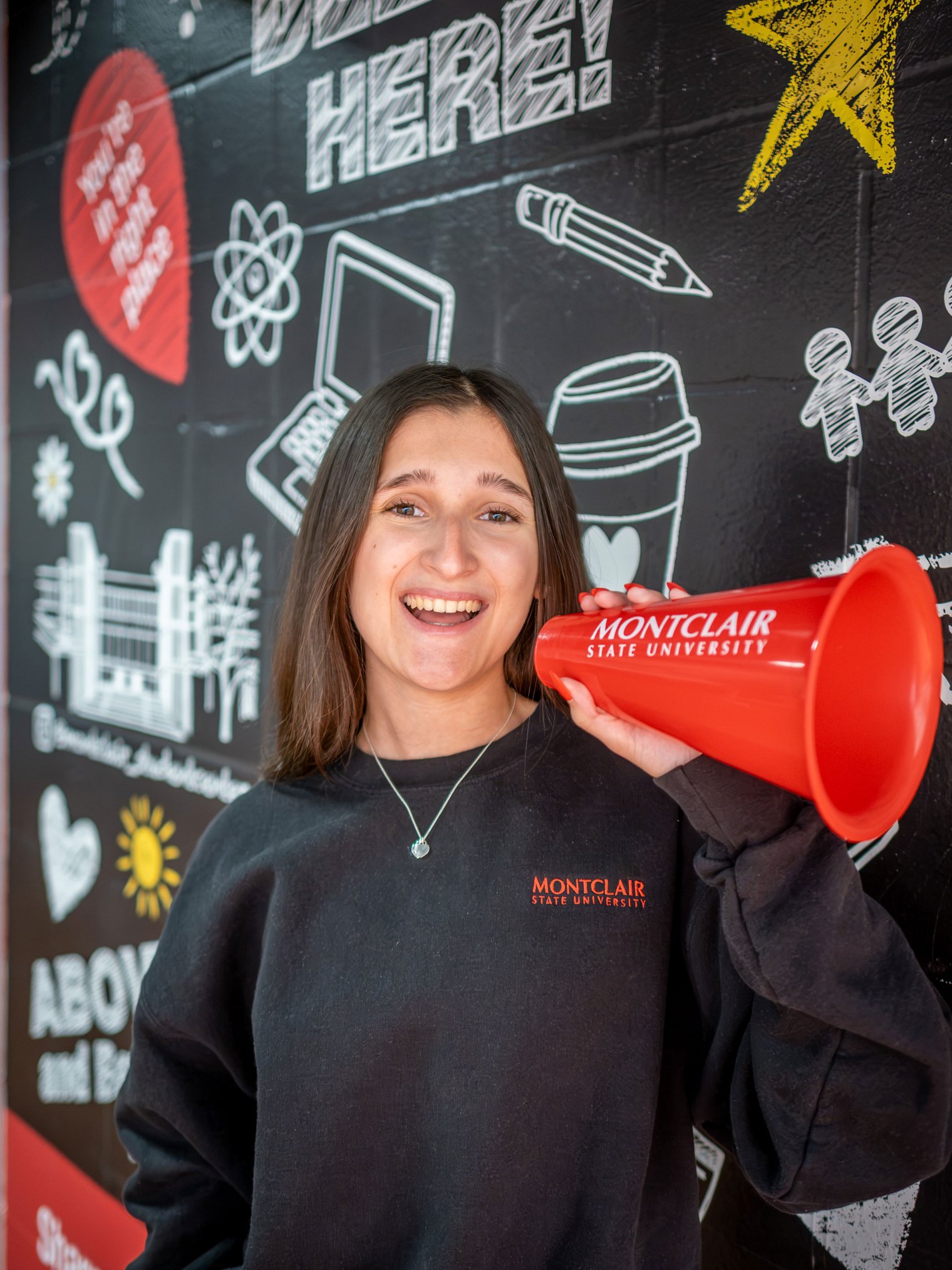 Photo of Madison Garcia smiling at the camera and holding up a red mini megaphone.