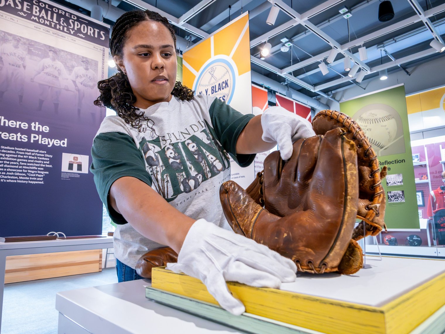 Ella Sumners handles replica mitts from the 1940s at the Muth Museum.