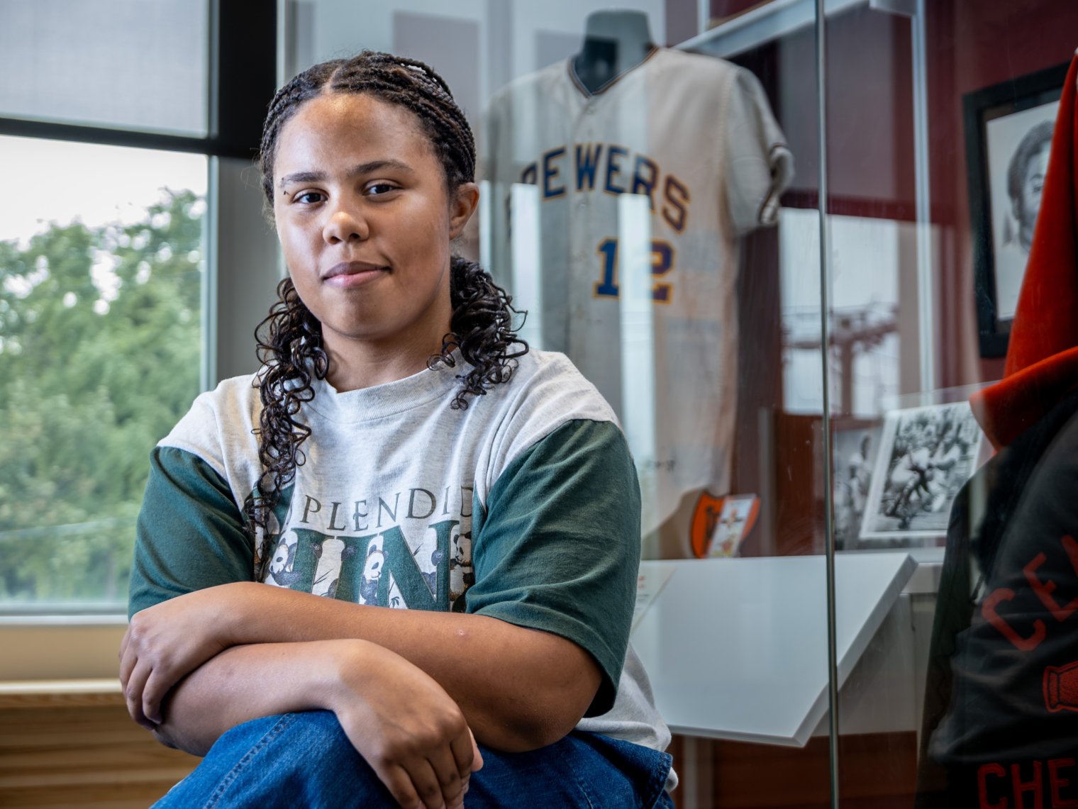 Ella Sumners sits in front of baseball memorabilia.