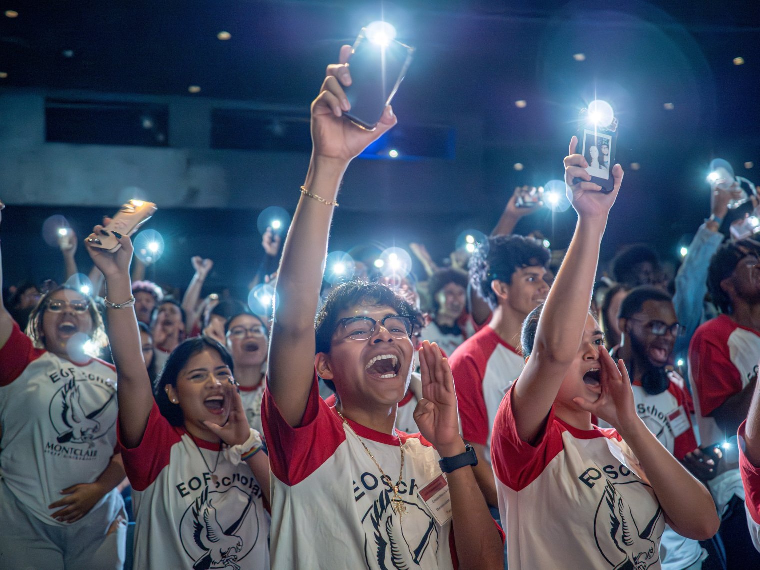 Students cheer and shine the lights on their phones.