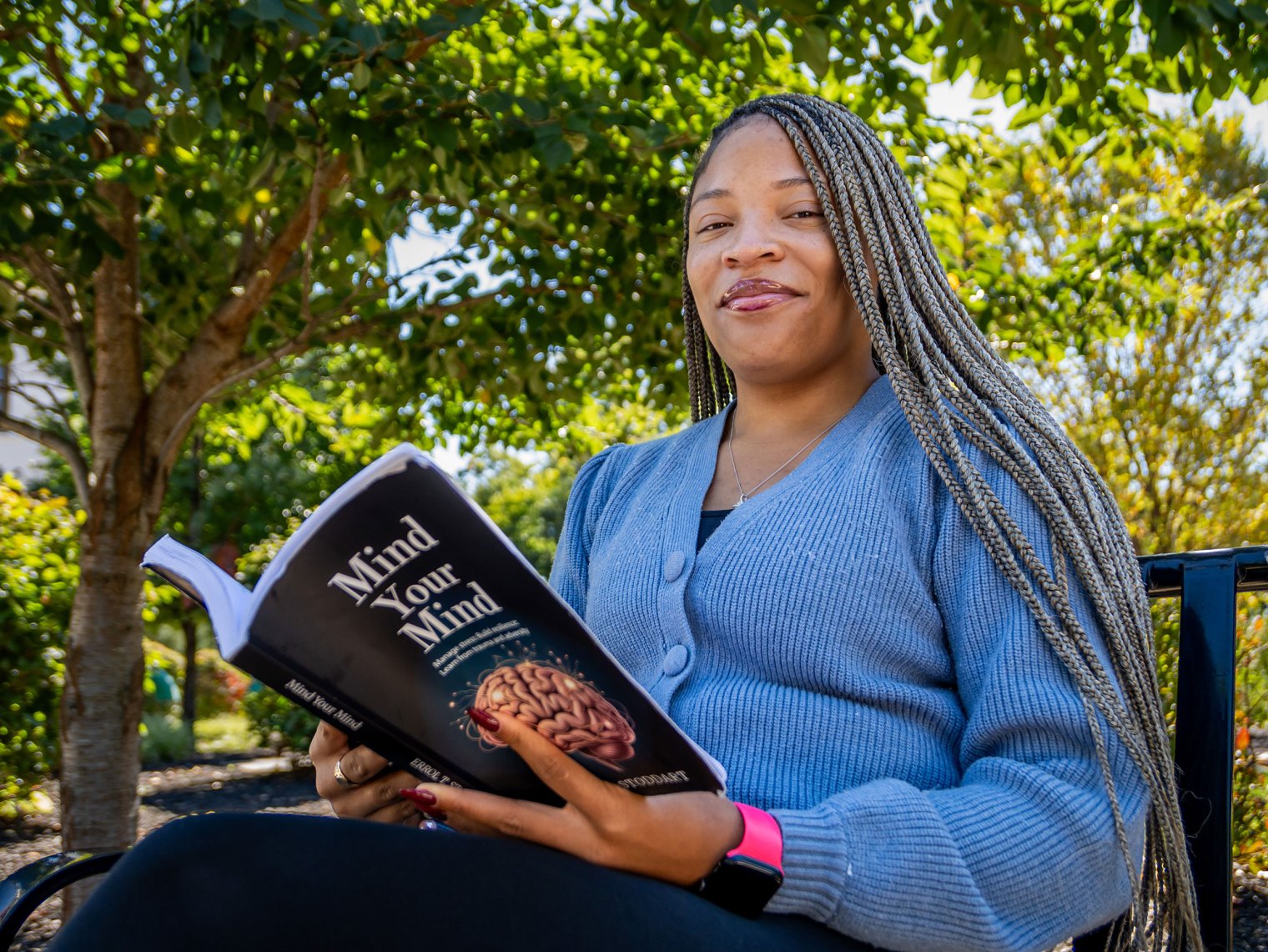 Josephine Leonards holds a book as she sits on a campus bench.