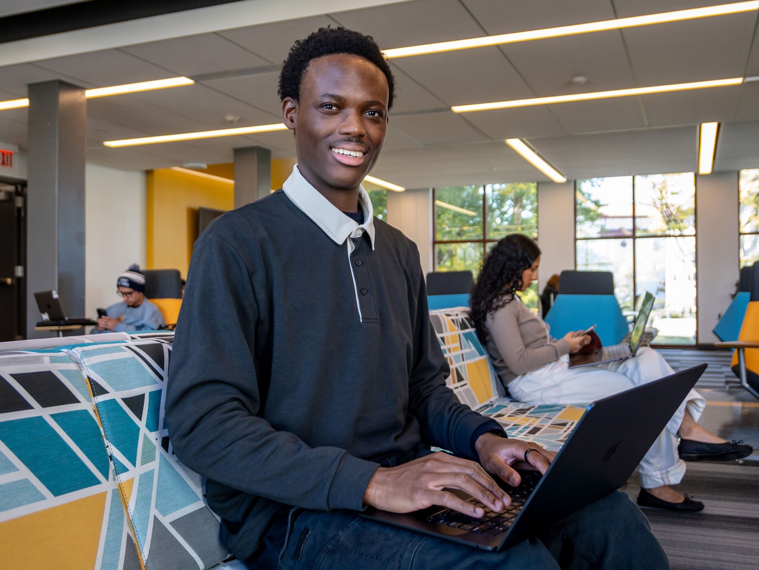 Jonathan Asare sits with a laptop.