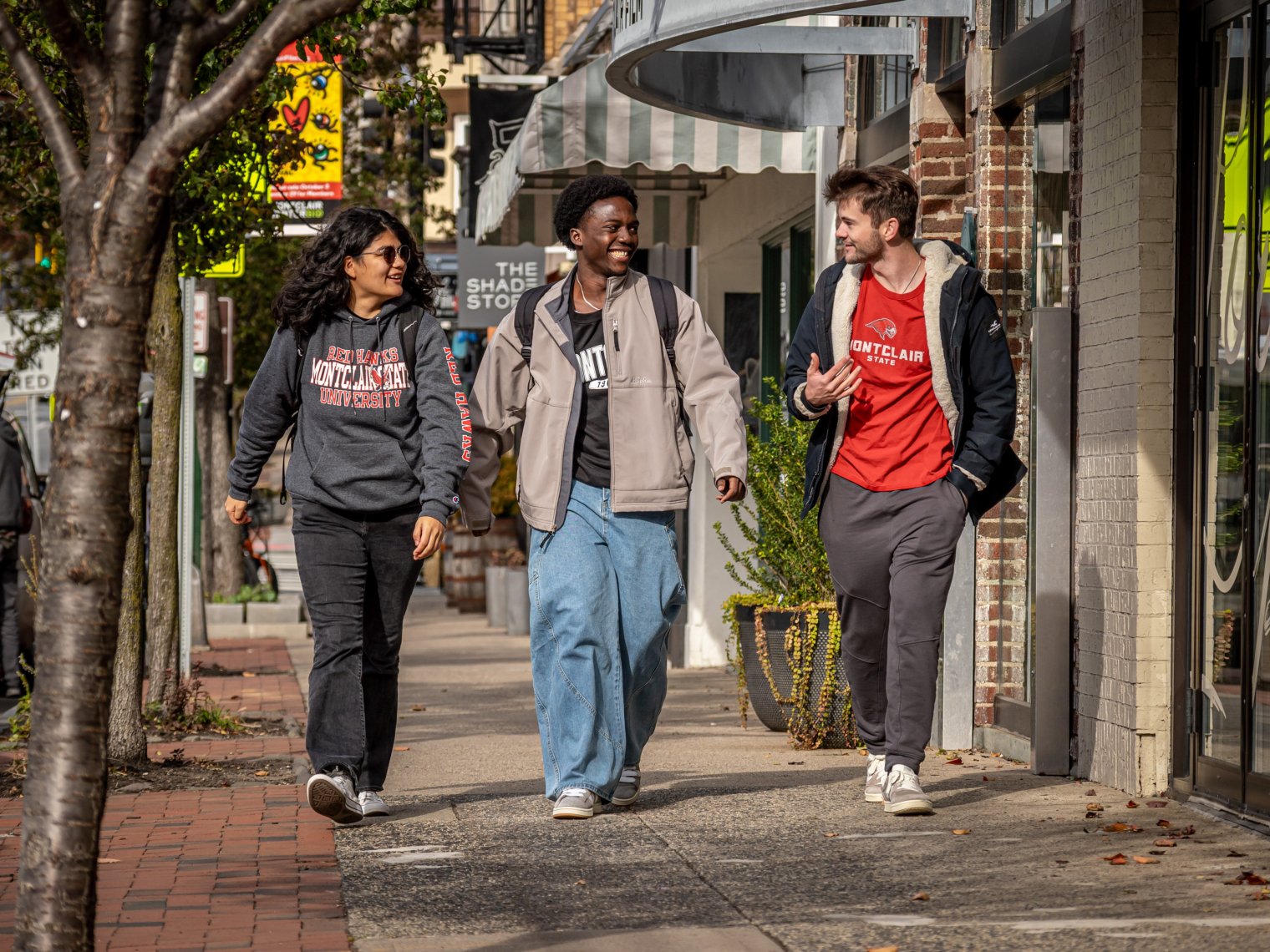 Three students walk on a street in Montclair.
