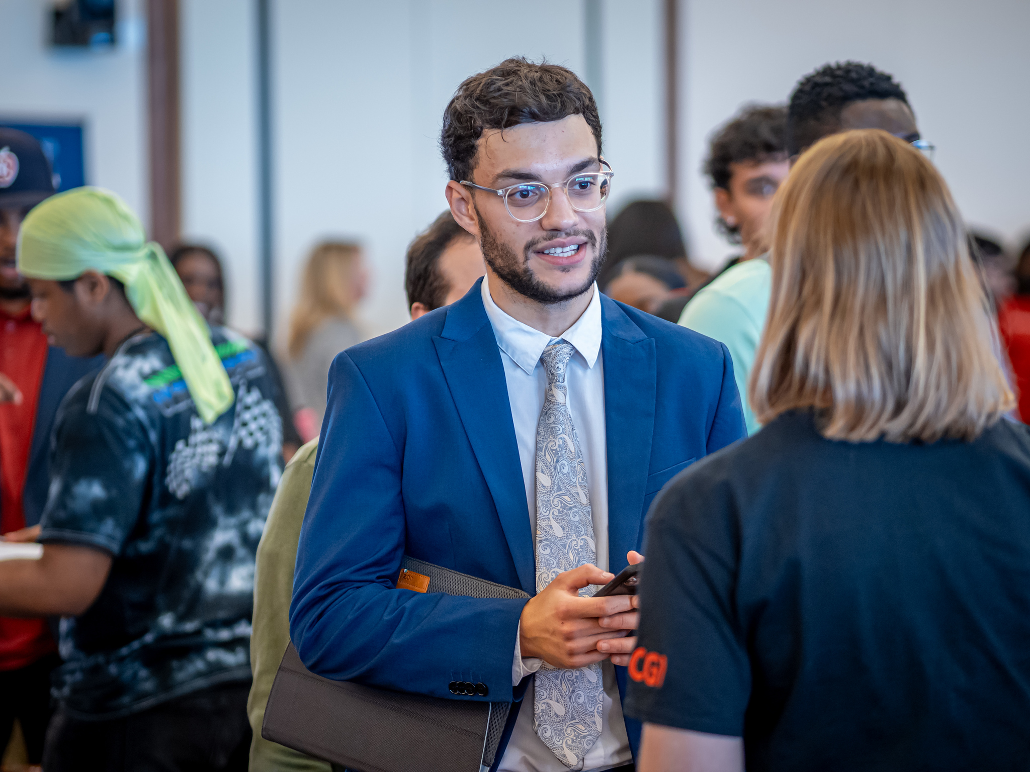 Male student wearing a blue suit and tie talking to an employer representative at a Career Fair