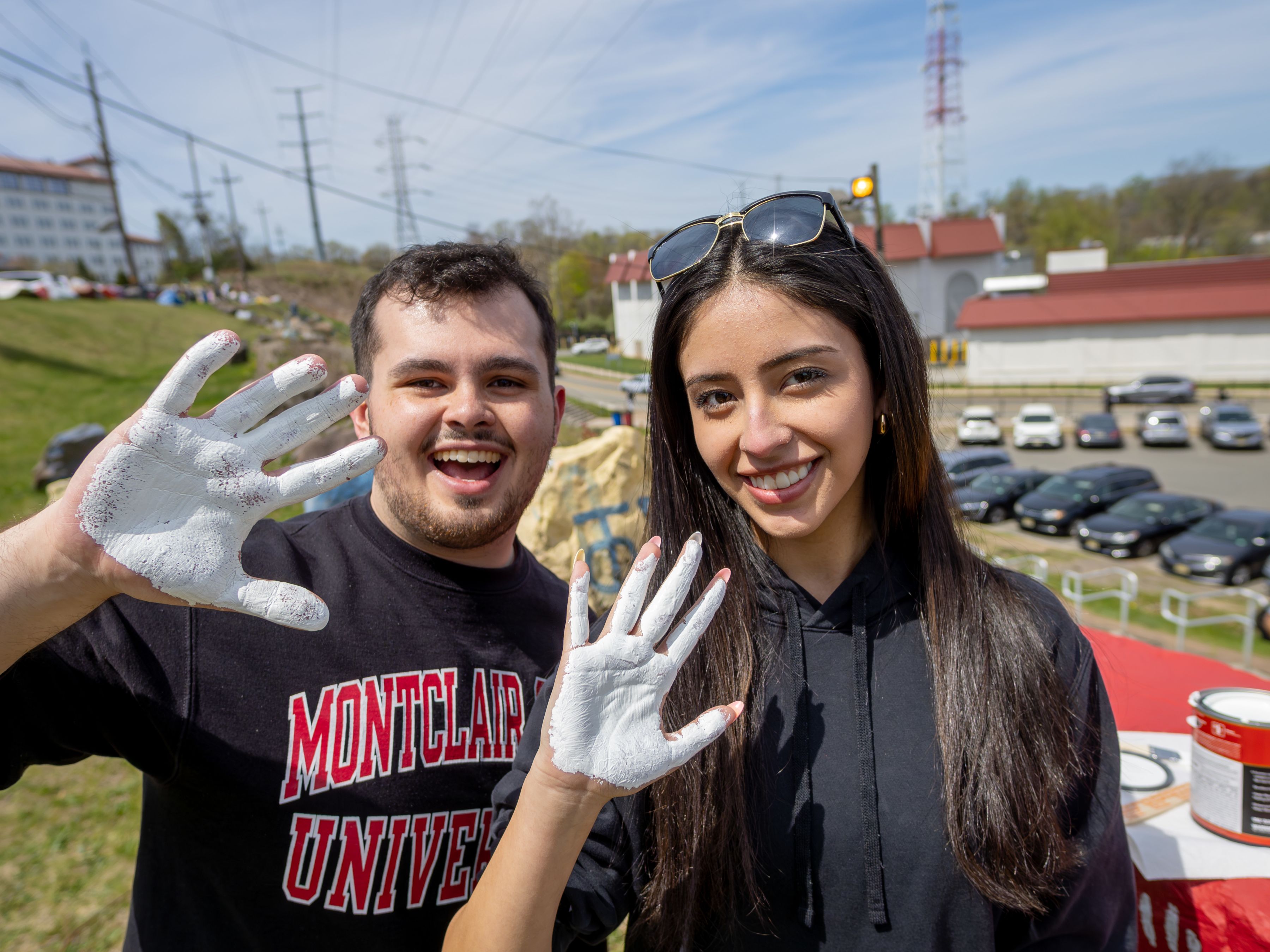 Two social media ambassadors hold up their hands which are covered in white paint