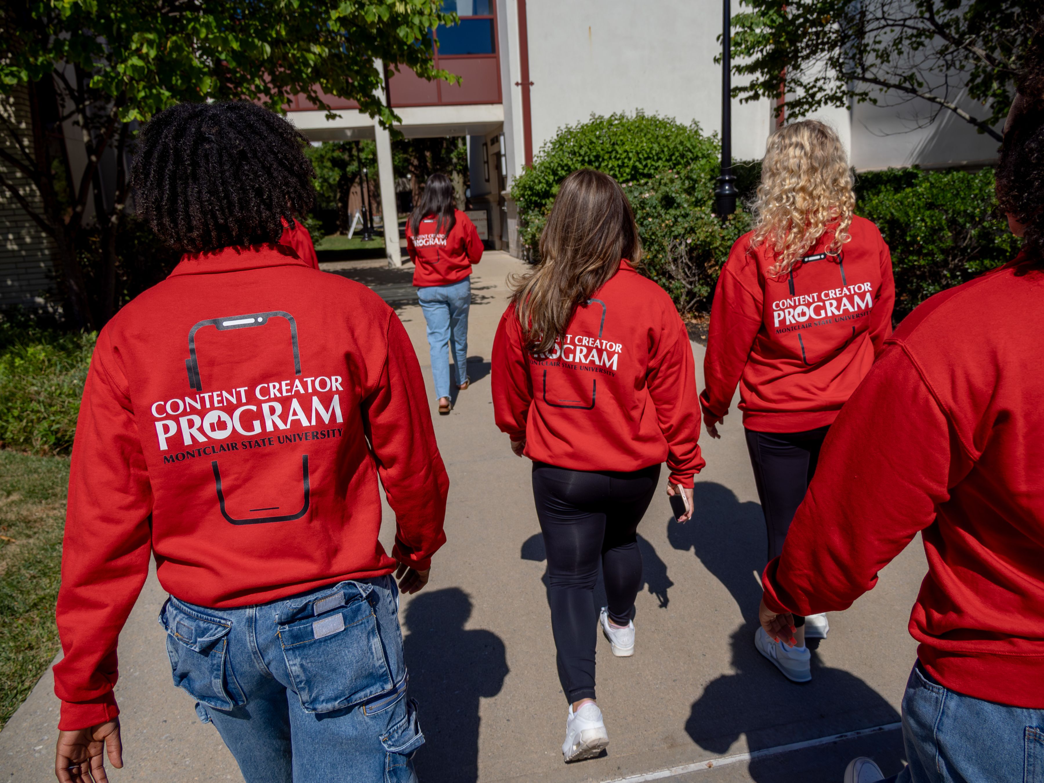 Social media ambassadors walking down the walkway wearing red sweatshirts