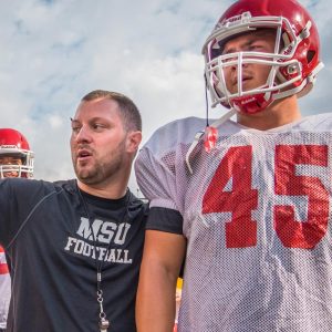 Photo of football coach and student athlete at practice.